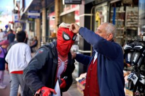 A local shopkeeper places his hat on Ayaz Koç, dressed as Spider-Man, Osmaniye, southern Türkiye, March 30, 2024. (AA Photo)