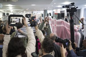 Participants try to prevent journalists from filming and photographing before the start of the Palestine Congress 2024 by holding up kufiyas and scarves, Friday, April 11, 2024. (Sebastian Christoph Gollnow/dpa via AP)