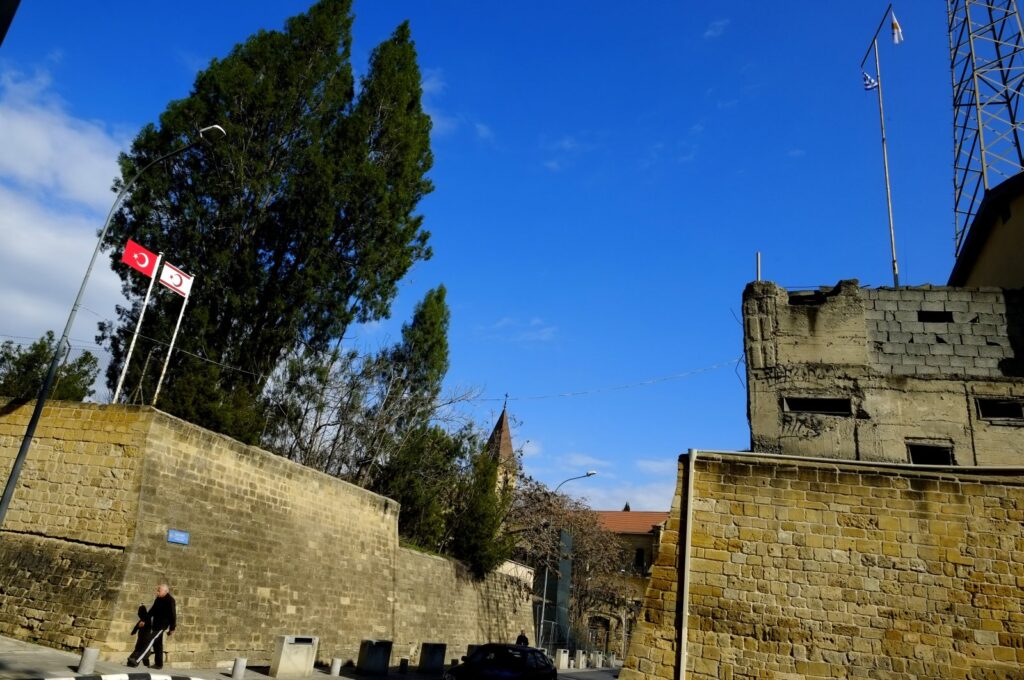 A man walks inside the U.N. buffer zone between the Venetian walls as a Turkish flag flies at the top left next to the Turkish Cypriot flag, in Lefkoşa (Nicosia), Cyprus, Jan. 28, 2022. (AP Photo)