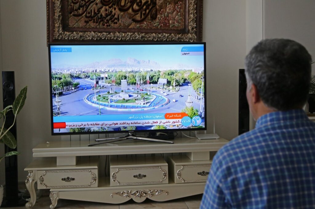A man watches an Iranian media announcement of an explosion in the region of Isfahan province, which hosts the Iranian Air Force Base, Iran, April 19, 2024. (AA Photo)
