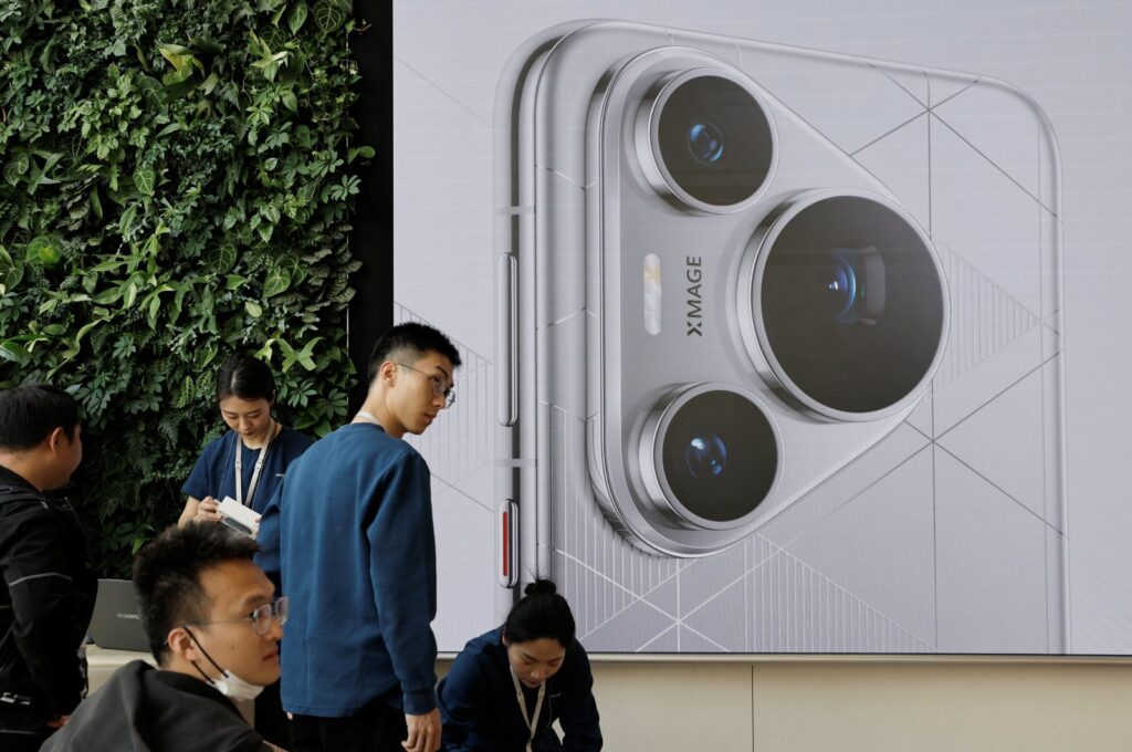 People stand near a screen showing the new Huawei Pura 70 series smartphone as the series models go on sale at Huawei's flagship store, Beijing, China, April 18, 2024. (Reuters Photo)