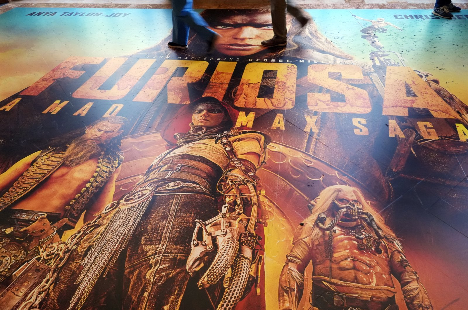 Attendees walk over a floor advertisement for the upcoming film "Furiosa: A Mad Max Saga" on the opening day of CinemaCon 2024, Caesars Palace, Las Vegas, Nevada, U.S., April 8, 2024. (AP Photo)