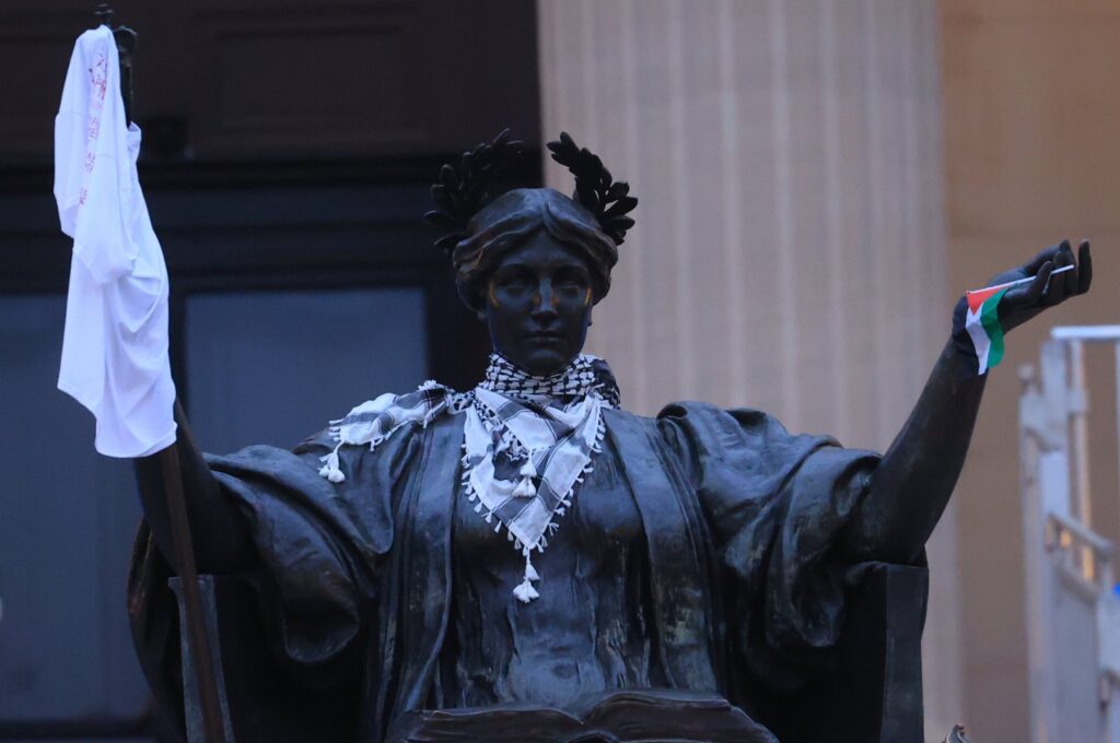 A stature in front of Columbia University's Hamilton Hall carry the keffiyeh and the Palestinian flag during protests, in New York, U.S., April 30, 2024. (AA Photo)