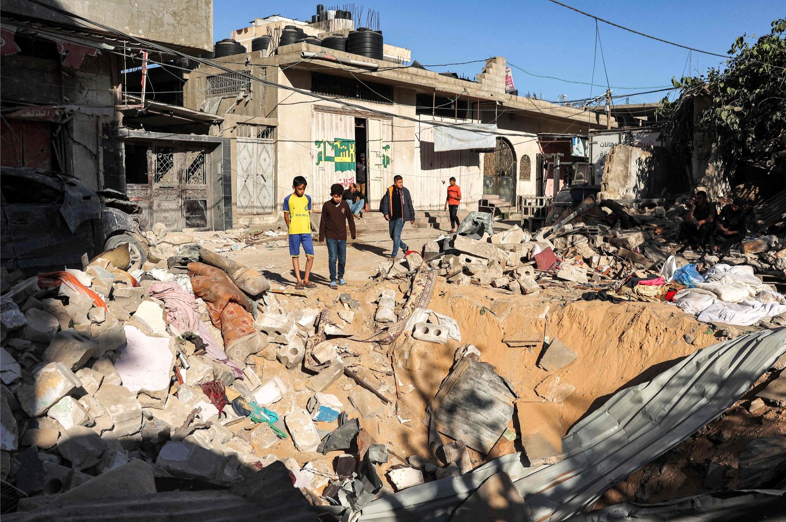 Children stand by an impact crater at the site of a building that was hit by Israeli bombardment in Rafah in the southern Gaza Strip on May 8, 2024. (AFP Photo)