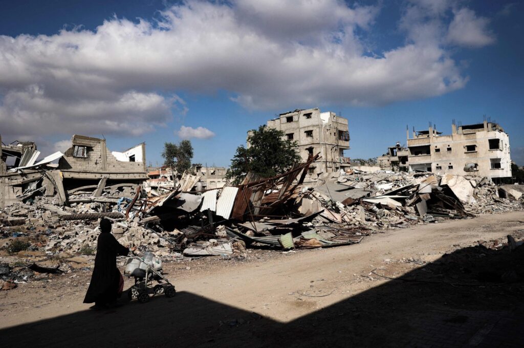 A displaced Palestinian woman pushes a stroller as she walks in front of destroyed buildings in Khan Younis, Gaza Strip, Palestine, May 16, 2024. (AFP Photo)