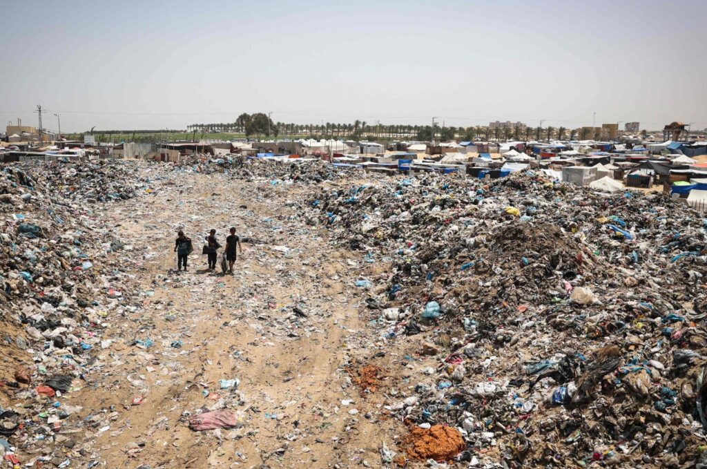 Children walk with bags of objects found in garbage piled up near tents set up by Palestinians displaced by Israeli attacks in Khan Younis in the southern Gaza Strip, May 18, 2024. (AFP Photo)