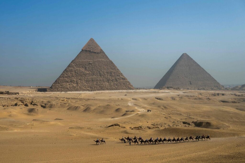 Tourists ride camels past the Great Pyramid of Khufu (Cheops, R) and the Pyramid of Khafre (Chephren, L) at the Giza Pyramids Necropolis on the outskirts of Giza, Egypt, May 3, 2024. (AFP Photo)