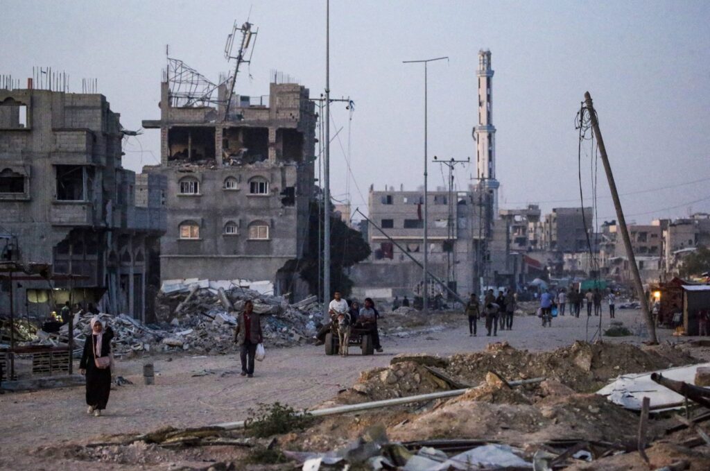 Internally displaced Palestinians walk next to buildings destroyed by Israel in Khan Younis town, southern Gaza Strip, 31 May 2024. (EPA Photo)