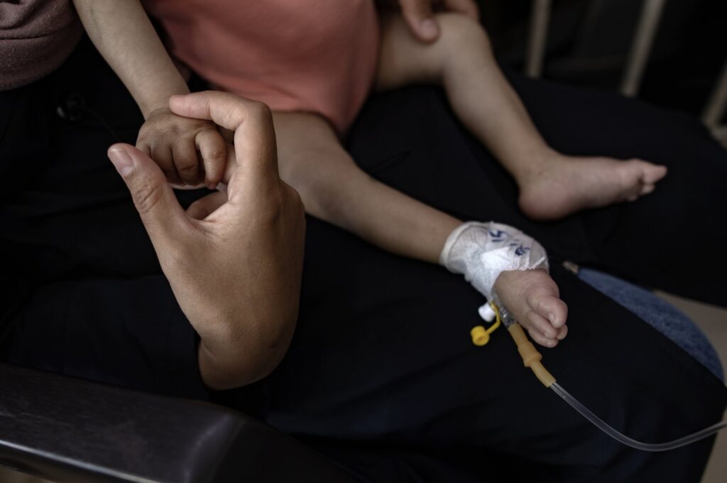Palestinian child Yousef al-Jojo sits on his mother's lap as she holds his hand at Al-Aqsa Martyrs Hospital in Deir al-Balah, Gaza Strip, June 1, 2024. (EPA Photo)