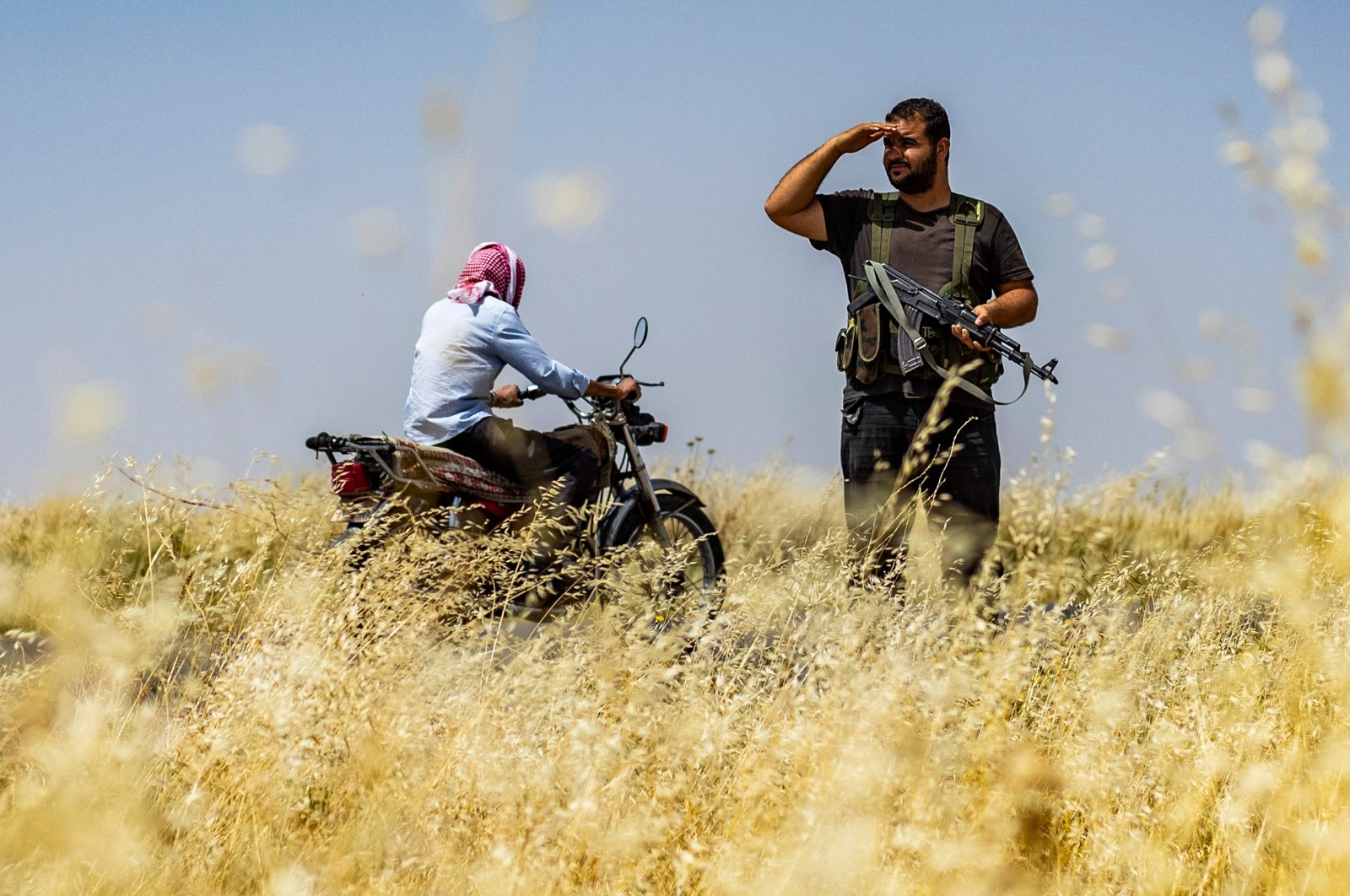 A man rides a bike past a member of the PKK/YPG in Hassakeh, Syria, May 30, 2024. (AFP Photo)