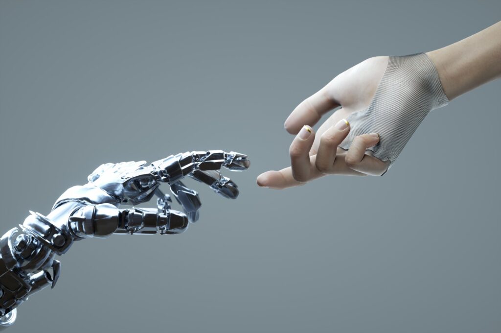 Digital generated image of female hand touching robotic hand against grey background. (Getty Images Illustration)