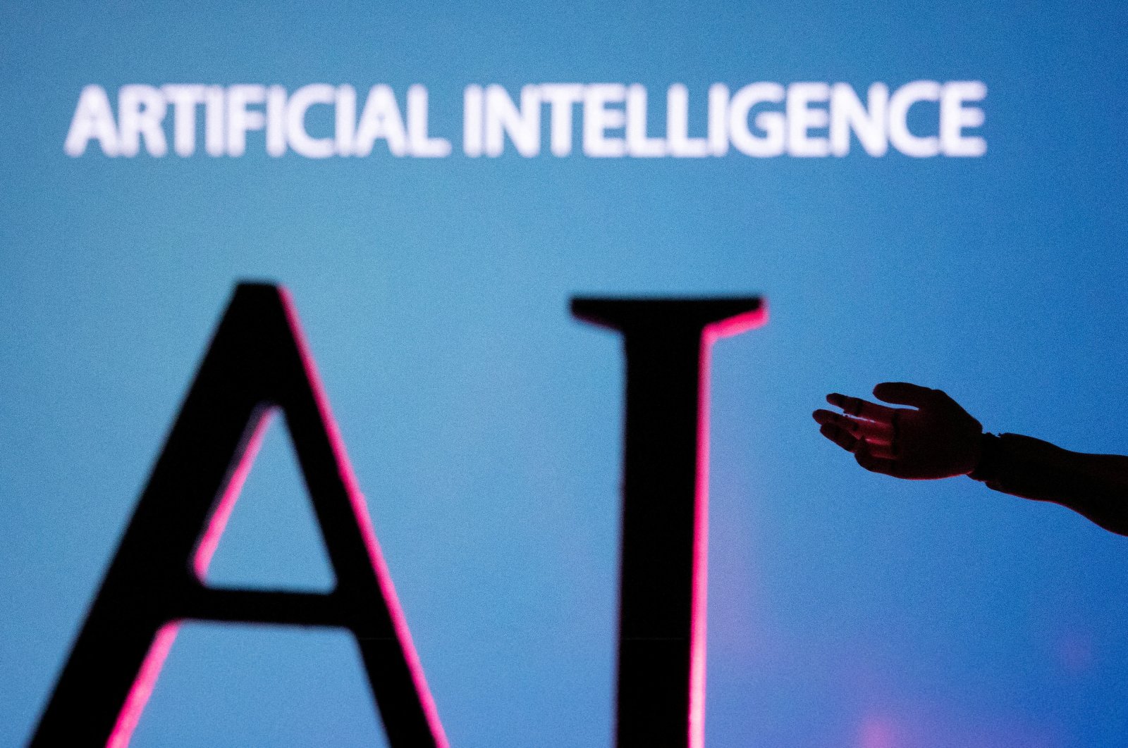 Artificial Intelligence letters and robot hand miniature are seen in this illustration taken on June 23, 2023. (Reuters Photo)