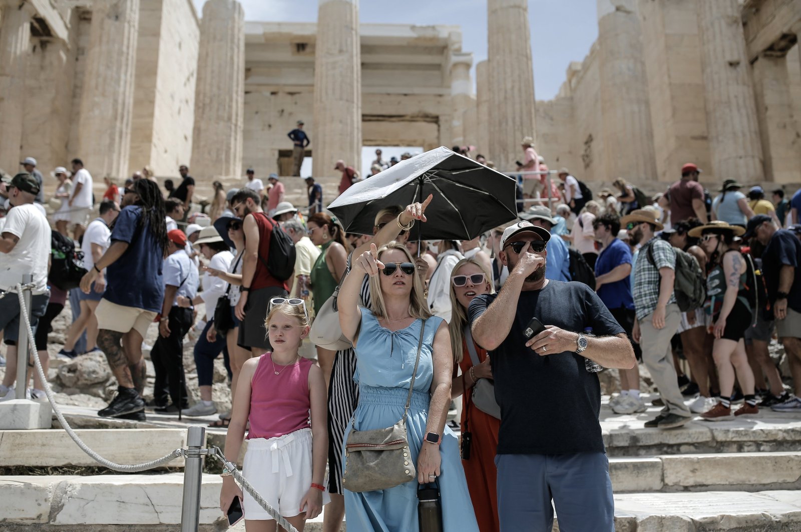 A tourist guide shades herself under an umbrella as she tours a family around the Acropolis archaeological site, Athens, Greece, June 11, 2024. (EPA Photo)