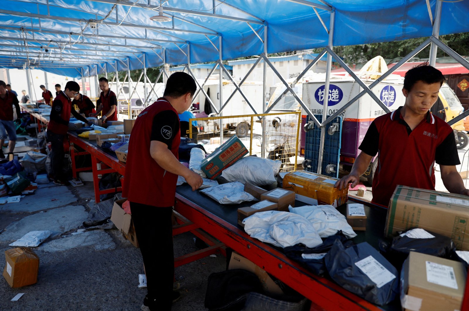 Delivery workers sort packages on a conveyor belt ahead of the "618" shopping festival at a logistics station in Beijing, China, June 12, 2023. (Reuters Photo)