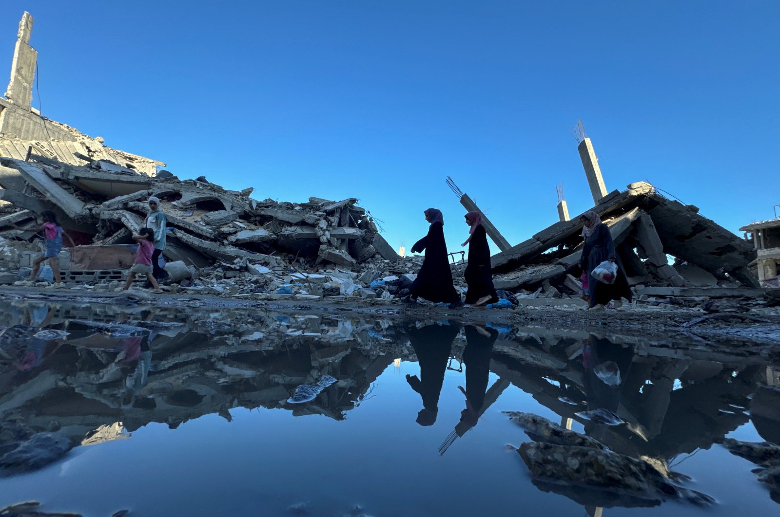 Palestinians walk past the rubble of houses destroyed in Israeli strikes, in Khan Younis in the southern Gaza Strip July 7, 2024. (Reuters Photo)
