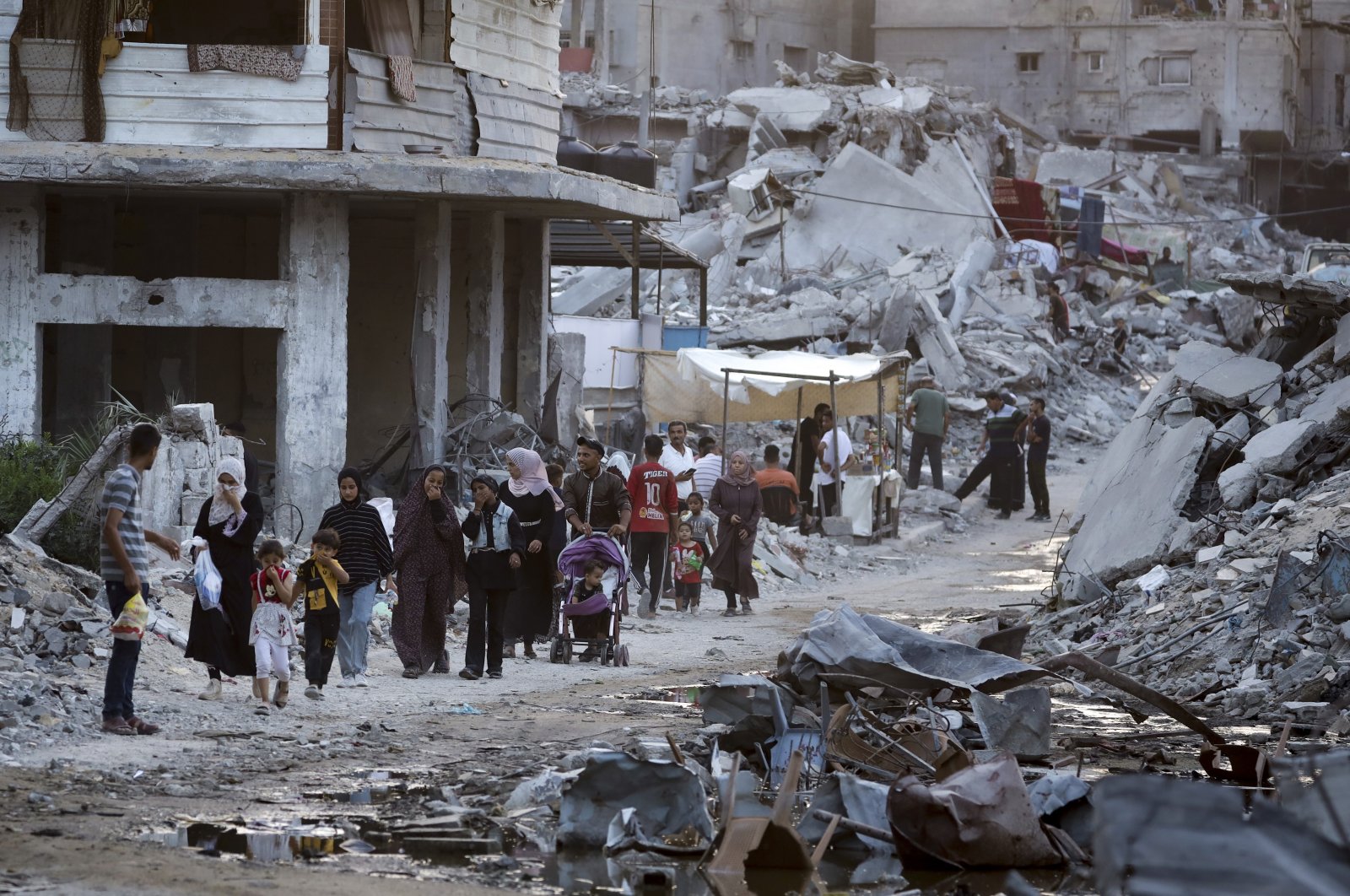Palestinians displaced by the Israeli air and ground offensive on the Gaza Strip walk next to sewage flowing into the streets of the southern town of Khan Younis, Gaza Strip, July 4, 2024. (AP Photo)