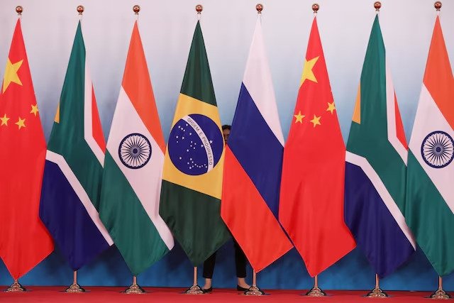 A staff worker stands behind the national flags of Brazil, Russia, China, South Africa and India to tidy the flags before a group photo during the BRICS Summit at the Xiamen International Conference and Exhibition Center in Xiamen, southeastern China's Fujian Province, China, Sept. 4, 2017. (Reuters Photo)