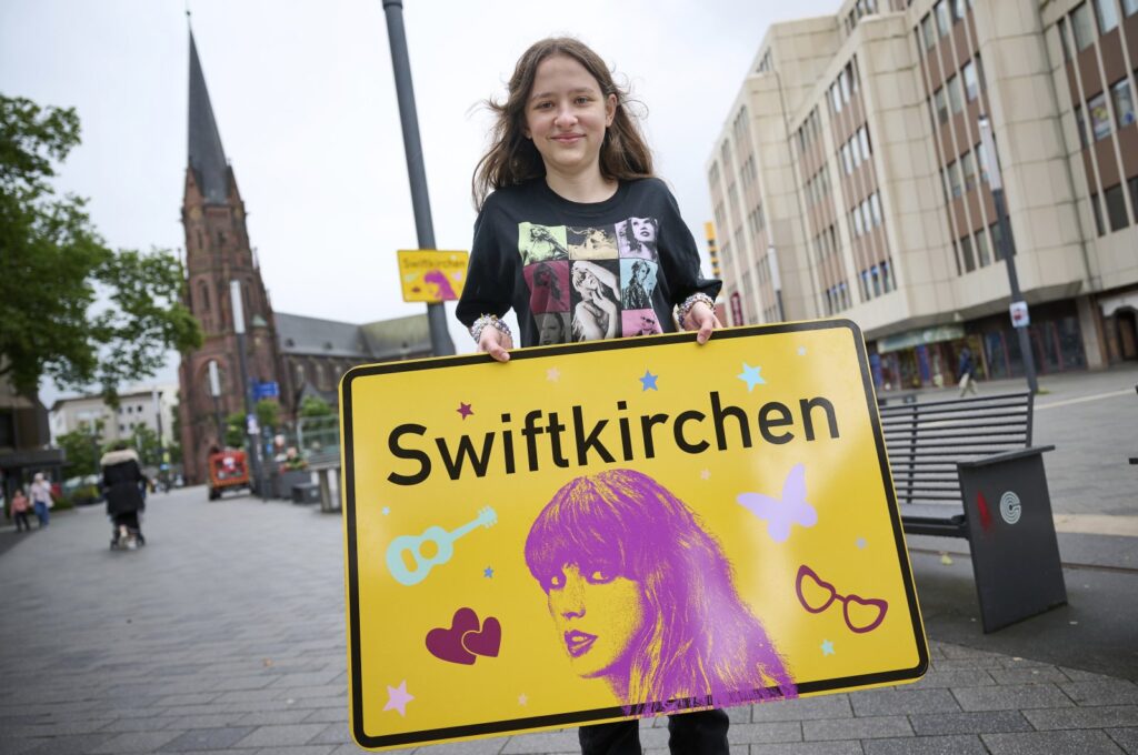 Schoolgirl Aleshanee Westhoff shows a "Swiftkirchen" town sign in honor of musician Taylor Swift in Gelsenkirchen, Germany, July 2, 2024. (AP Photo)