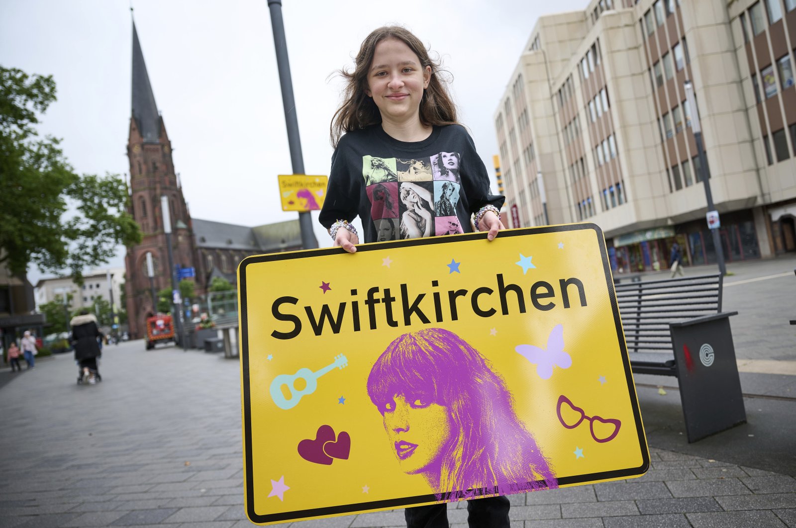 Schoolgirl Aleshanee Westhoff shows a "Swiftkirchen" town sign in honor of musician Taylor Swift in Gelsenkirchen, Germany, July 2, 2024. (AP Photo)