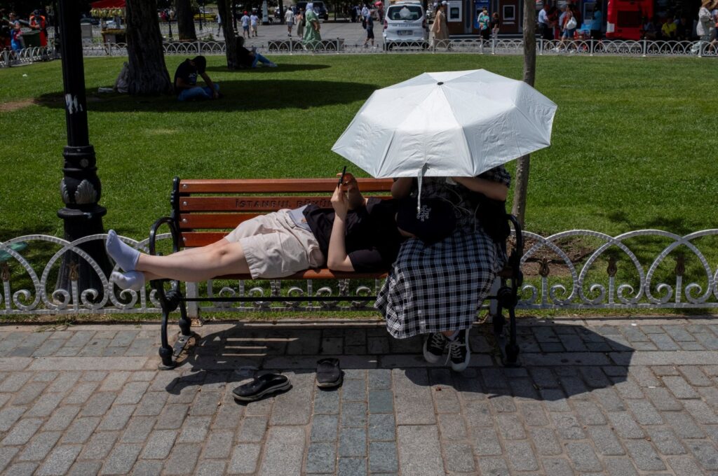 People shelter from the sun with an umbrella as they pause at Sultanahmet Square, one of the city's most well-known tourist attractions, Istanbul, Türkiye, June 28, 2024. (Reuters Photo)