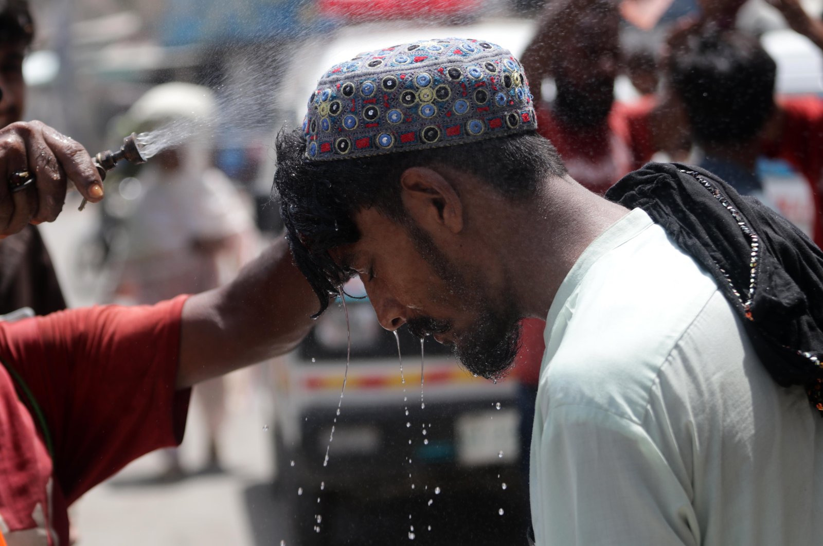 A worker of the Edhi Foundation sprays cool water on people along a street on a hot day, Karachi, Pakistan, June 25, 2024. (EPA Photo)