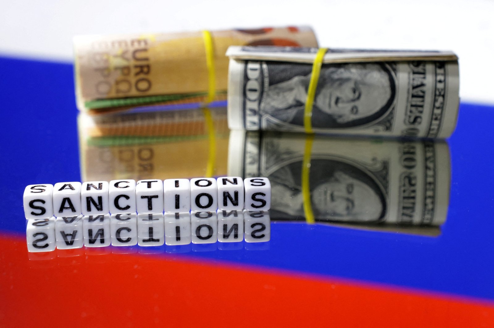 Euro and dollar banknotes and the words "Sanctions" are placed on the Russian flag in this illustration taken on May 16, 2024. (Reuters Photo)
