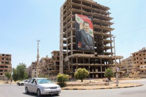 Vehicles pass near a poster depicting Syrian leader Bashar Assad, Douma, Syria, June 19, 2023. (Reuters Photo)