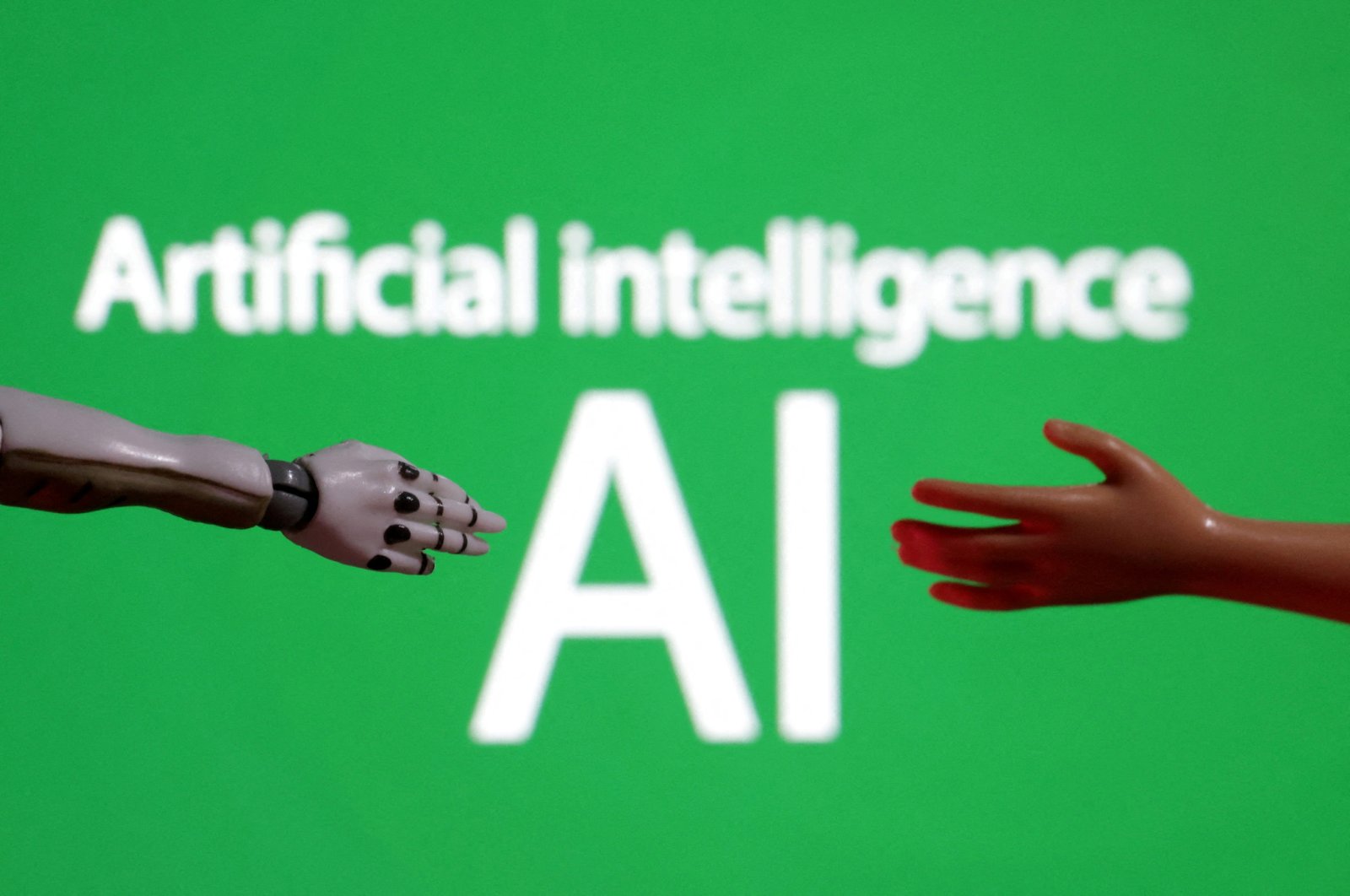 Words reading "Artificial intelligence AI," and miniatures of robot and toy hands are pictured in this illustration taken on Dec. 14, 2023. (Reuters Photo)