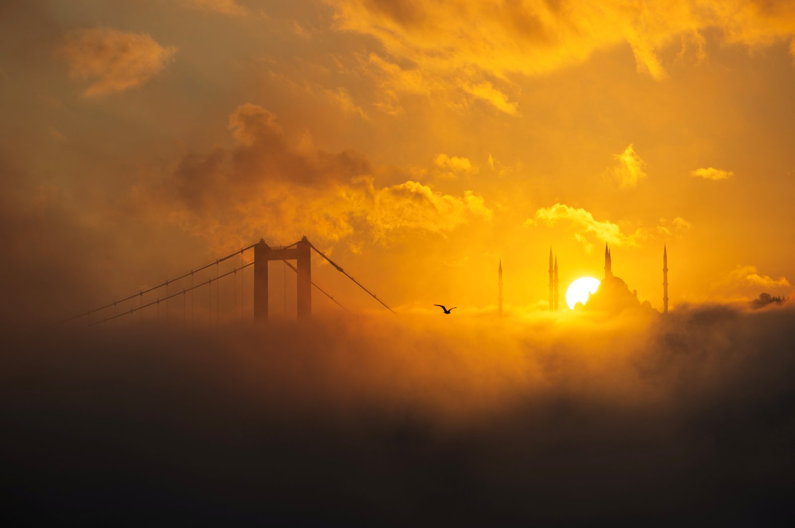 The sun rises behind the Grand Çamlıca Mosque as the July 15 Martyrs' Bridge and the Bosporus are covered in fog, Istanbul, Türkiye, Oct. 16, 2024. (Reuters Photo)