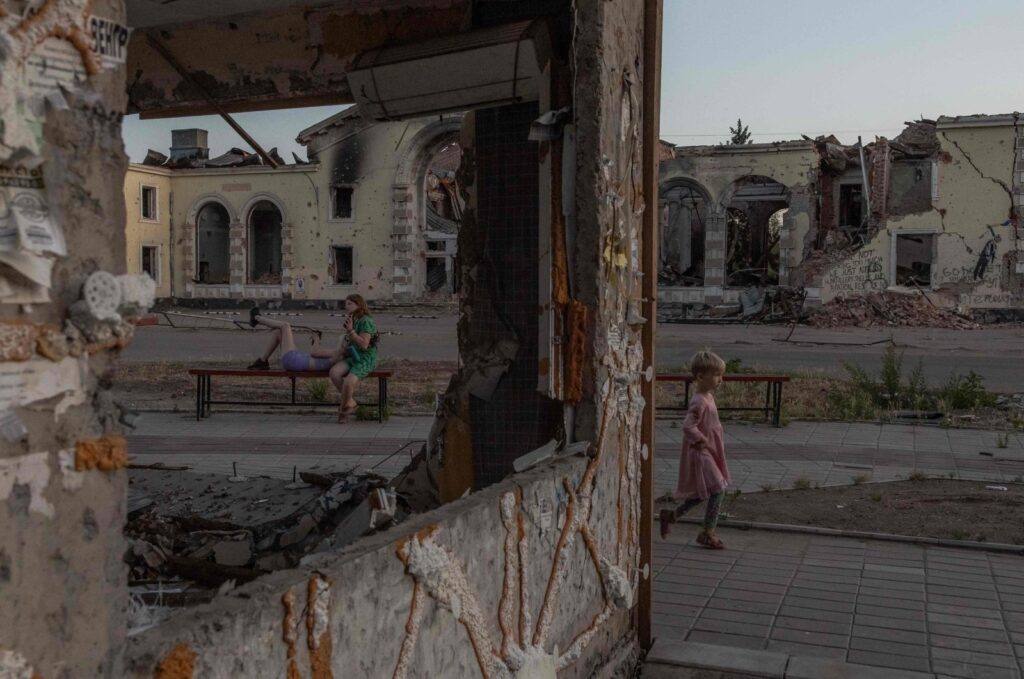 A child plays as women rest on a bench in front of residential buildings destroyed by shelling in Kostyantynivka, eastern Donetsk region, Ukraine, June 22, 2024. (AFP Photo)