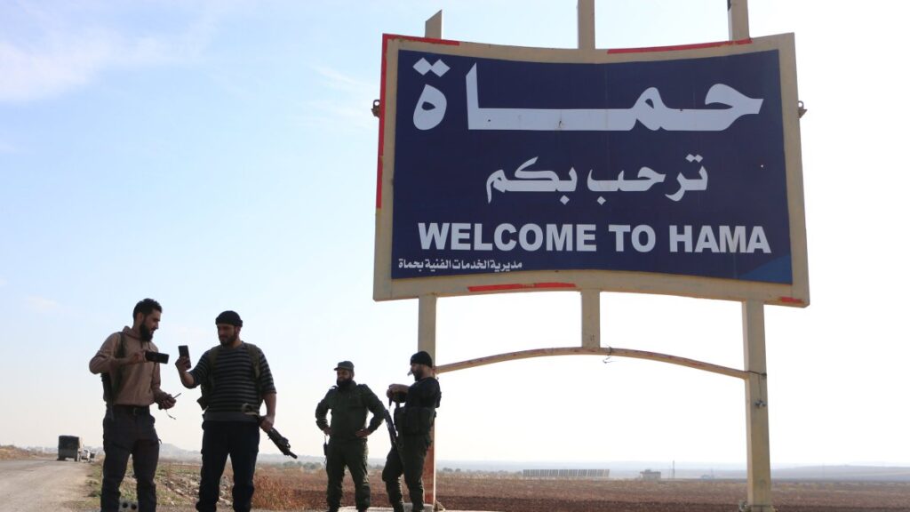 Members of anti-regime forces pose in front of a sign near Hama, Syria, Dec. 3, 2024. (AA Photo)