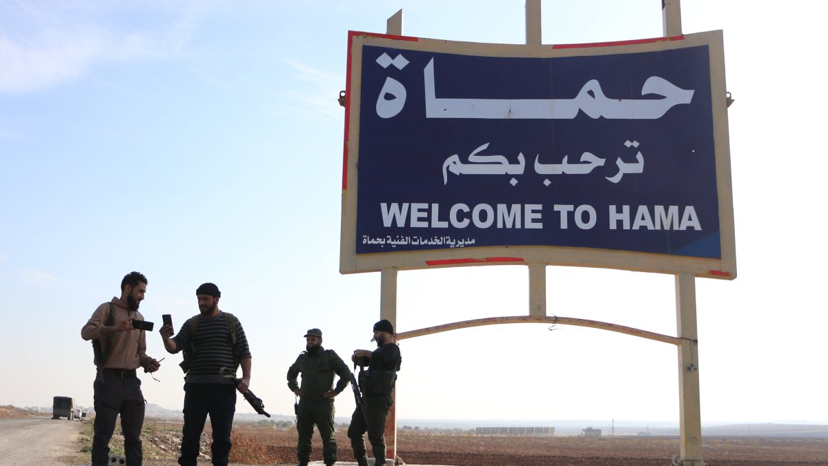 Members of anti-regime forces pose in front of a sign near Hama, Syria, Dec. 3, 2024. (AA Photo)