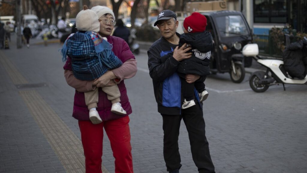 Two elders carry toddlers as they walk down a street, Beijing, China, Jan. 17, 2025. (EPA Photo)