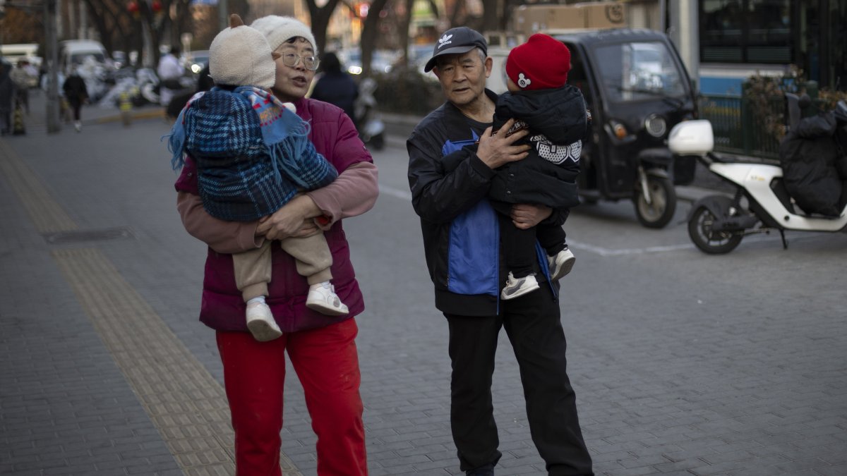 Two elders carry toddlers as they walk down a street, Beijing, China, Jan. 17, 2025. (EPA Photo)