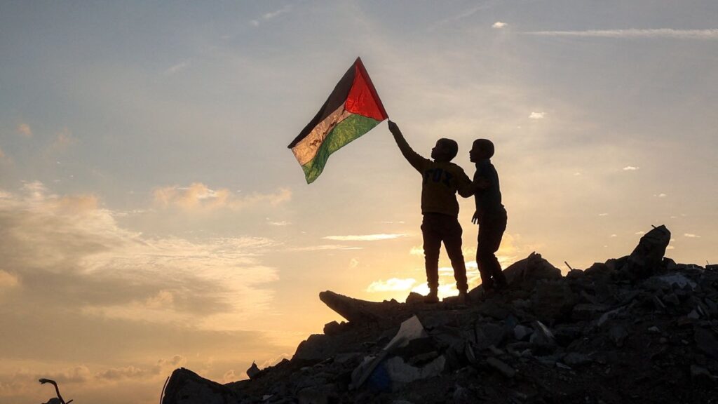 A boy runs with a Palestinian flag atop a mound of rubble at a camp for people displaced by Israel's attacks in Bureij in the central Gaza Strip, Jan. 17, 2025. (AFP Photo)