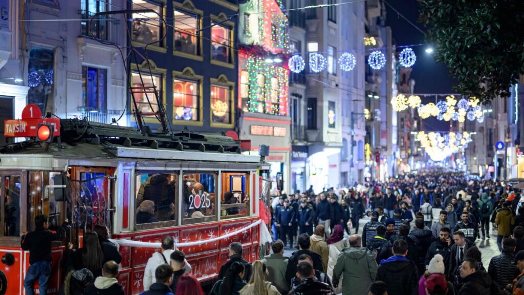 People walk past a historic tram on Istiklal Street on New Year's Eve, Istanbul, Türkiye, Dec. 31, 2024. (AFP Photo)