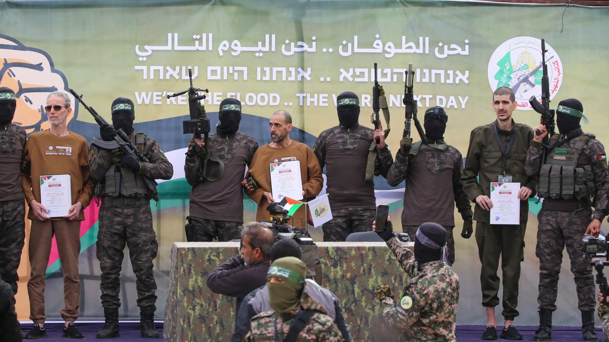 Palestinian Hamas fighters escort Israeli hostages (L-R, holding certificates) Ohad Ben Ami, Or Levy and Eli Sharabi on a stage before handing them over to a Red Cross team in Deir el-Balah, central Gaza, Feb. 8, 2025. (AFP Photo)