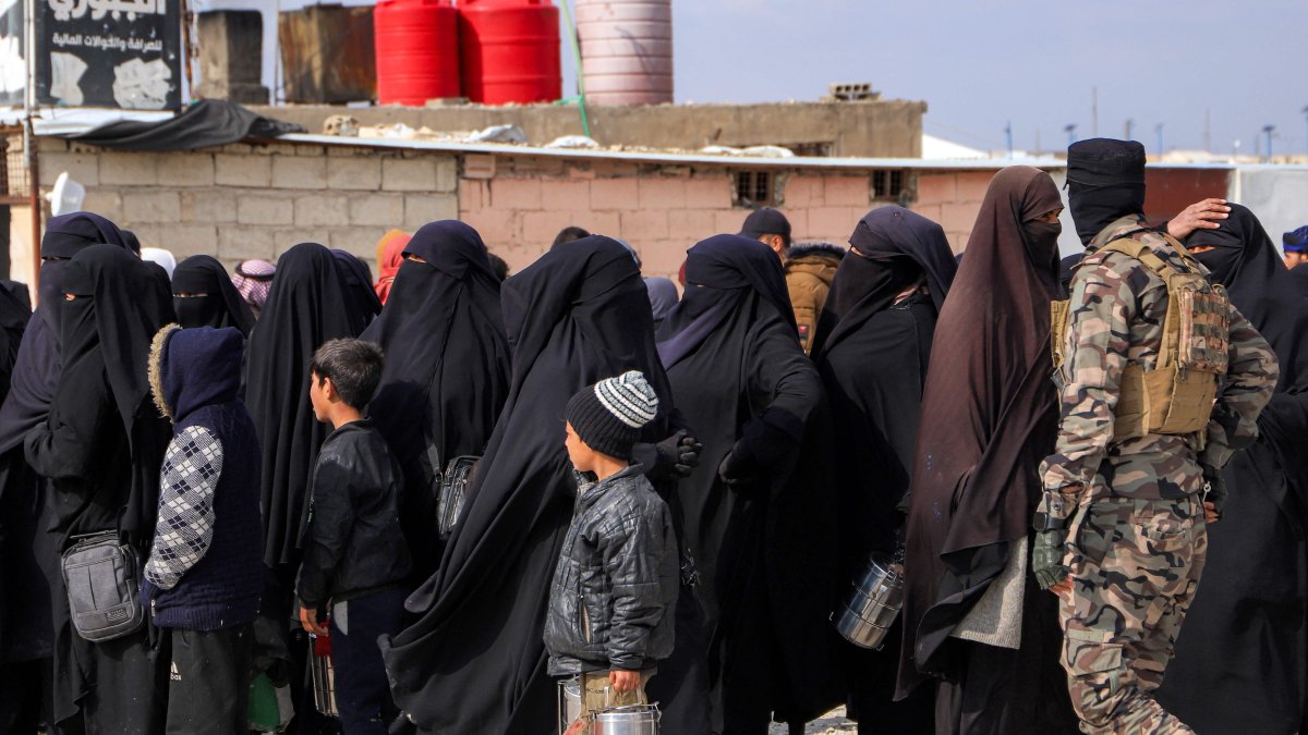 A U.S.-backed PKK/YPG terrorist passes in front of women and children queueing at the al-Hol camp, northeastern Hassakeh province, Syria, Feb. 9, 2025. (AFP Photo)