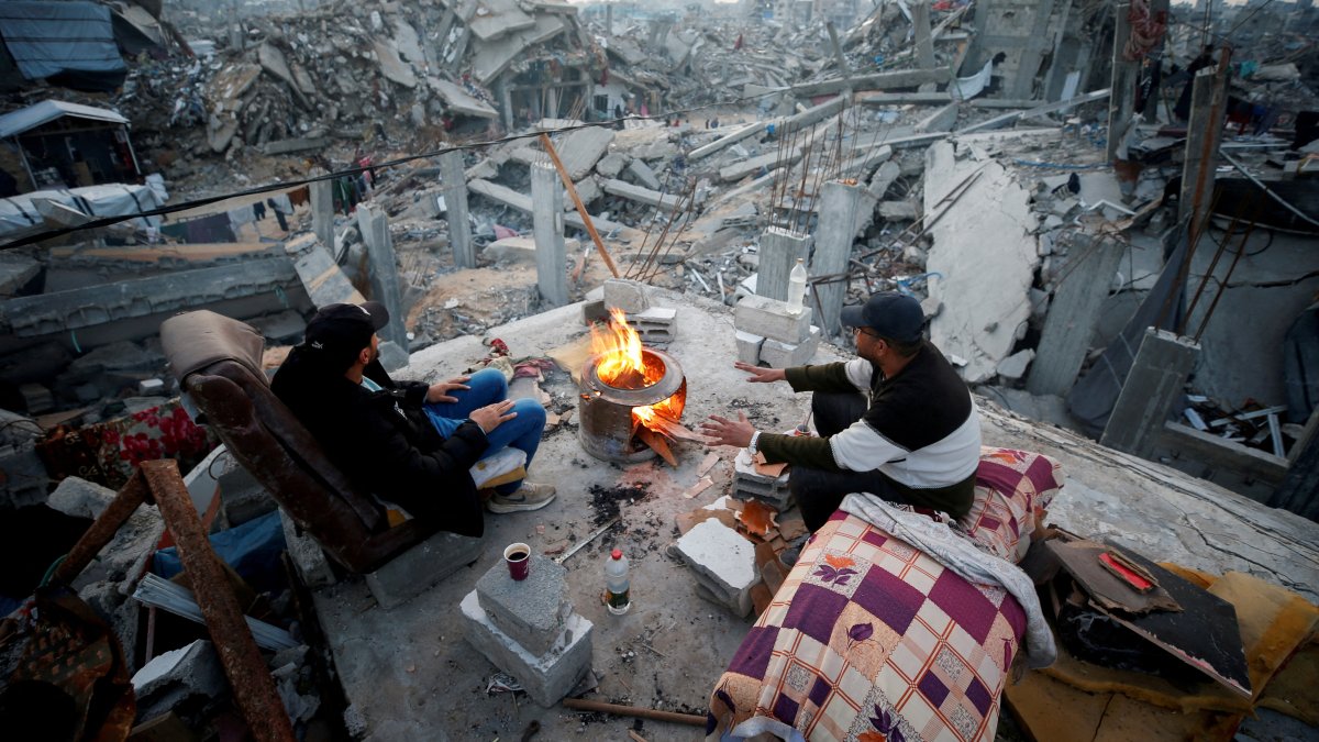 Palestinians sit next to a fire among the rubble of buildings destroyed during the Israeli offensive, at Jabalia refugee camp, northern Gaza Strip, Palestine, Feb. 17, 2025. (Reuters Photo)