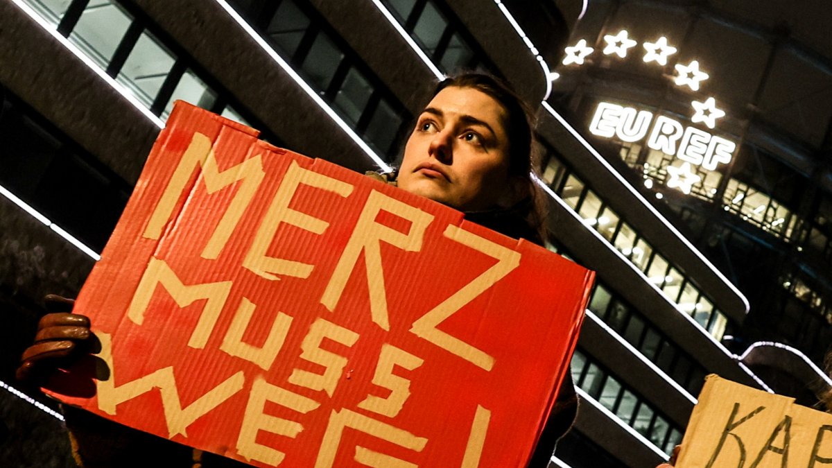 A woman holds a banner that reads "Merz must go" against Chair of the Christian Democratic Union (CDU) party and chancellor candidate Friedrich Merz during an election campaign event, Berlin, Germany, Feb. 20, 2025. (EPA Photo)