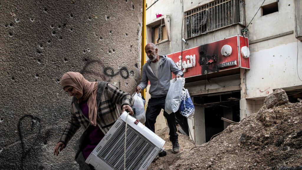 Displaced Palestinians carry personal belongings they retrieved from their home as they walk past a bullet-riddled wall in the Jenin camp for refugees, occupied West Bank, Palestine, Feb. 24, 2025. (AFP Photo)