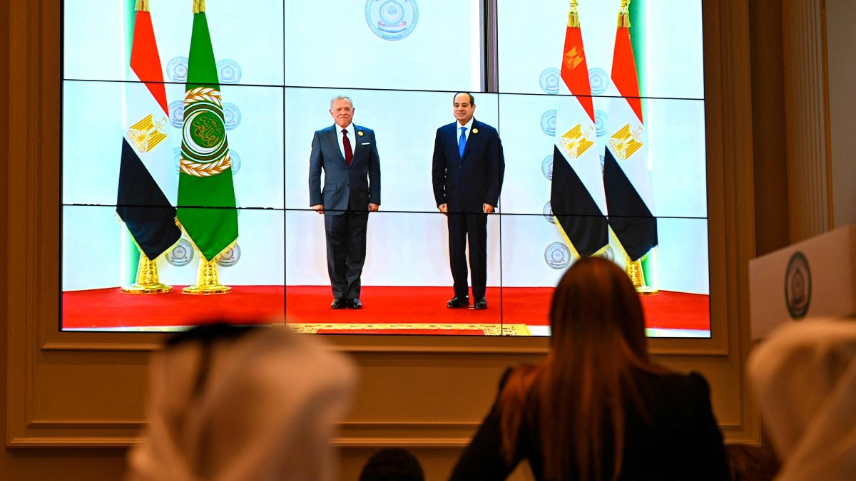 People watch on a big screen as Egypt's President Abdel Fattah el-Sissi (R) welcomes Jordan's King Abdullah II ahead of an Arab League summit on Gaza on March 4, 2025. (AFP Photo)