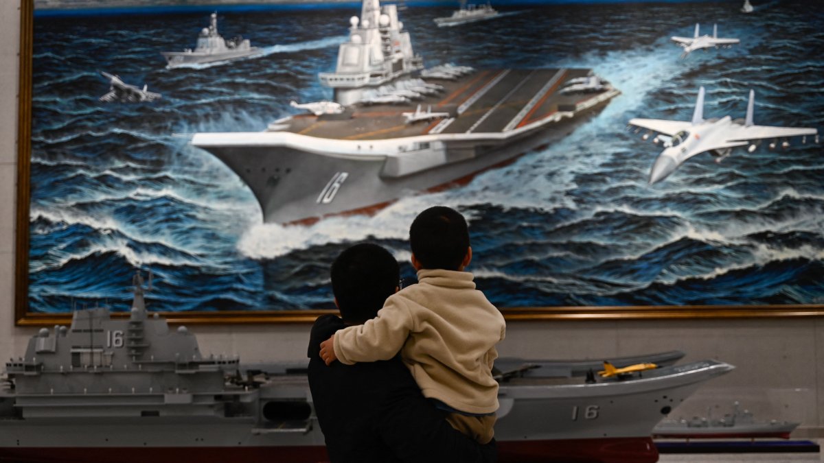 People look at a model and painting of China’s Liaoning aircraft carrier at the Military Museum in Beijing, China, March 2, 2025. (AFP Photo)