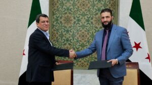 Syria's interim President Ahmed al-Sharaa and YPG leader Ferhat Abdi Şahin shake hands, after Syria reached a deal to integrate the SDF with state institutions. March 10, 2025. (Handout via Reuters)
