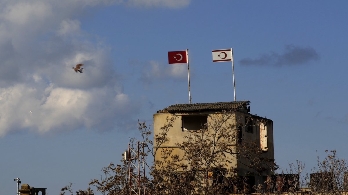 A pigeon flies next of an abandoned military guard post with a Turkish (L) and the Turkish Cypriot flags, in the northern part of Nicosia (Lefkoşa), Cyprus, Feb. 2, 2024. (AP Photo)