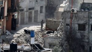 An Israeli soldier looks on as a military excavator demolishes a building in the Nur Shams camp for Palestinian refugees east of Tulkarem, amid an ongoing offensive in the occupied-West Bank, March 6, 2025. (AFP Photo)