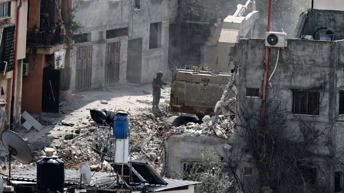 An Israeli soldier looks on as a military excavator demolishes a building in the Nur Shams camp for Palestinian refugees east of Tulkarem, amid an ongoing offensive in the occupied-West Bank, March 6, 2025. (AFP Photo)