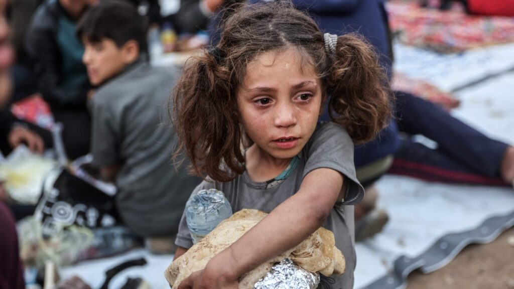 A Palestinian child carrying food cries as people gather for a mass fast-breaking iftar meal in Beit Lahia in the northern Gaza Strip, March 15, 2025. (AFP Photo)