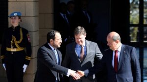 The Greek Cypriots leader Nikos Christodoulides (L) and Turkish Cypriot President Ersin Tatar (R) shake hands after a meeting in the presence of U.N. Cyprus representative Colin Stewart (C), Lefkoşa (Nicosia), island of Cyprus, Jan. 20, 2025. (Reuters Photo)