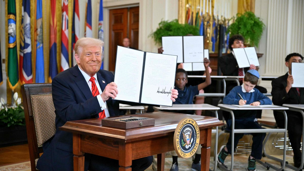 U.S. President Donald Trump holds an executive order after signing it alongside U.S. Secretary of Education Linda McMahon (R) in the East Room of the White House, Washington, U.S., March 20, 2025. (AFP Photo)